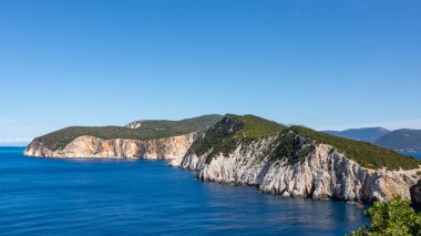Panoramik mavi deniz ve yeşil kayalık uçurumlar, Yunanistan 'da açık bir günde güneşli sahil. Manzaralı seyahat yeri. Lefkada adası, İyon deniz kıyısı