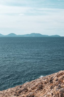 Uzak adaların dikey zeminine sahip mavi renkli İyon deniz manzaralı kayalık bir uçurum. Yunanistan 'ın Lefkada adasında yaz doğası. Renk sınıflandırılmış