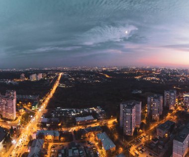 Arabalar, Sarzhyn yar üzerinde karamsar, aydınlık bir köprü kullanıyor. Kharkiv şehrinin hava akşam manzarası, Pavlove direği. Mahalle sokaklarında gece ışıkları ve gün batımından sonra bulutlu gökyüzü.