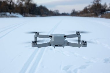 Kharkiv, Ukrayna - 21 Şubat 2021: Dji Maviç Mini 2 insansız hava aracı kış karlı havada gün batımında uçuyor. Yeni kuadkopter cihazı havada asılı duruyor. Arka plan, kayak pistinin üzerinden uç