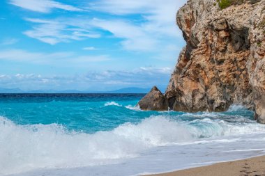 Beyaz köpüklü gök mavisi, canlı, fırtınalı dalgalar kayalık kıyıları kırıyor. Yunanistan 'ın Lefkada adasında dramatik gökyüzü olan Mylos plajı. Yaz doğası İyon Denizi 'ne seyahat