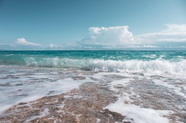 Yunanistan 'ın Lefkada adasının sahillerinde fırtınalı dalgalar ve destansı bulutlarla dolu çakıl taşı plajında parlayan beyaz köpük. İyon Denizi 'ne yaz seyahati. Renk sınıflandırılmış