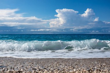 Yunanistan 'ın Lefkada adasının destansı sahillerinde, çakıl taşlı plajda beyaz köpüklü manzara dalgaları. Yaz doğası İyon Denizi 'ne seyahat