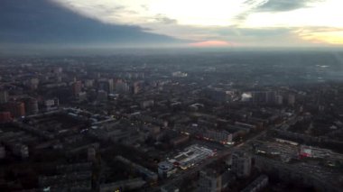 Kharkiv şehrinin Pavlove Pole semtinin yukarısındaki günbatımında hava sağından sol görüşe. Ufukta bulutlu gökyüzü olan gri çok katlı binalar