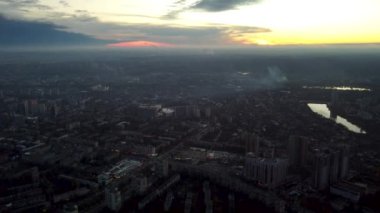 Kharkiv şehrinin Pavlove Pole bölgesindeki hava batımı görüntüleri. Ufukta parlak turuncu bulutlu gökyüzü olan gri çok katlı binalar