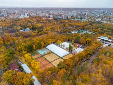 Children's Southern Railway Station near tennis courts in city center recreational park. Platform with train in yellow autumn forest. Aerial treetop view on Kharkiv, Ukraine