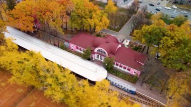 Güney Çocuk Tren İstasyonu 'nun üzerinde saat yönünde uç. Sarı sonbahar ormanlarında tren rayları ve platformları. Renkli Kharkiv 'de havadan ağaç manzarası, Ukrayna seferi