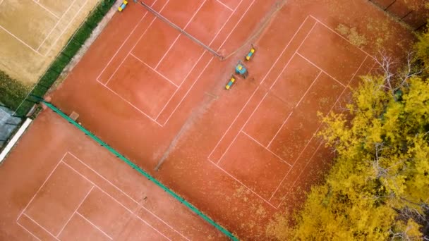 シティパークのオレンジクレイテニスコートの上でスパイラルアップしてください スポーツレクリエーションエリアの近くに鮮やかな黄色の秋の木 カラフルなハリコフの空中ツリートップビュー 旅行ウクライナ — ストック動画