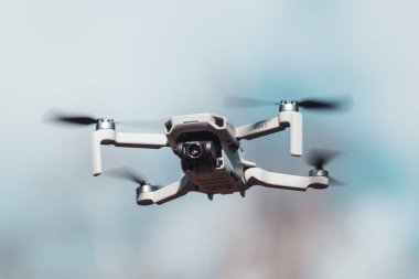Kharkiv, Ukrayna - 6 Mart 2021: Dji Maviç Mini 2 insansız hava aracı güneşli gün ışığında kamera merceği filtresiyle uçuyor. Bulanık bulutlu gökyüzü arkaplanında gezinen yeni dörtlü helikopter aygıtı