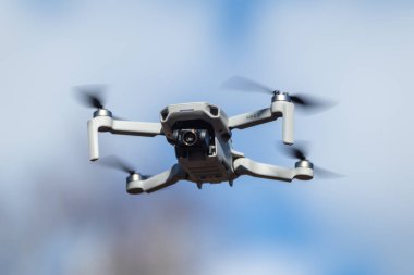 Kharkiv, Ukrayna - 6 Mart 2021: Dji Mavic Mini 2 insansız hava aracı kamera filtresi açık, güneşli mavi günde uçuyor. Bulanık bulutlu gökyüzü arkaplanında gezinen yeni dörtlü helikopter aygıtı