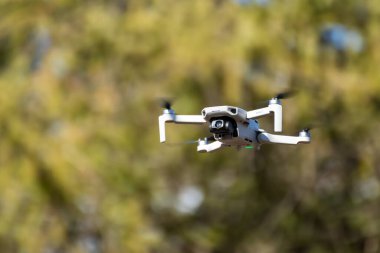 Kharkiv, Ukrayna - 6 Mart 2021: Dji Maviç Mini 2 insansız hava aracı, güneşli yeşillikte uçuyor. Bulanık yeşil arkaplan üzerinde gezinen yeni dörtlü helikopter aygıtı