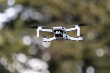 Kharkiv, Ukrayna - 6 Mart 2021: Dji Maviç Mini 2 insansız hava aracı, ormanda uçuyor. Bulanık ağaçlarla, bokeh arkaplanıyla gezen yeni dörtlü helikopter aygıtı