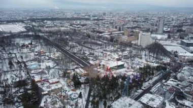 Kharkiv şehir merkezi, karlı beyaz kış, eğlence Gorky Central Park, İHA 4K görüntüler. Şehir sokaklarında hava manzarası ve dönme dolap eğlencesi