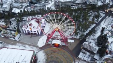 Kharkiv şehir merkezi Gorky Central Park 'ta hava karlı beyaz kış manzarası. Eğlence alanında çekimler ve dönme dolap var. İnsansız hava aracı görüntüleri