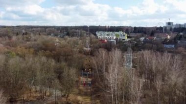 Bahar başındaki parktaki renkli kablo kulübelerinin hava görüntüsü. Güneşli bir günde Ukrayna, Kharkiv 'in dinlenme alanındaki ağaçların tepesinde.