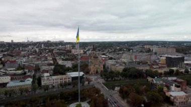 Bayrağın dalgalandığı Ukrayna bayrağına doğru git bayrak direğinde dalgalanan destansı bulut manzarasıyla. Ukrayna 'nın başkenti Kharkiv' deki Kutsal Annunciation Katedrali 'nin sonbaharda havadan görünüşü