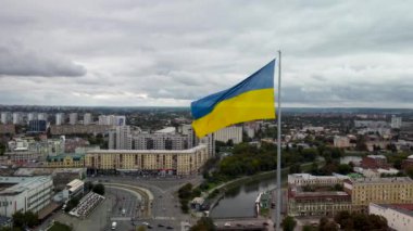 Bayrak direğinde dalgalanan Ukrayna bayrağı. Sonbahar şehri hava görüntüleri, Lopan nehri kıyısında merkez caddeler, Skver Strilka, Kharkiv, Ukrayna 'daki Pavlivska Meydanı