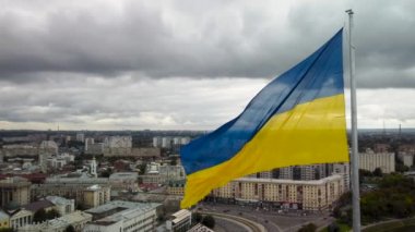 Ukrayna bayrağı yakın planda dalgalanıyor. Lopan nehri kıyısındaki merkez caddelerde sonbahar şehri hava manzarası, Skver Strilka, Kharkiv, Ukrayna 'daki Pavlivska Meydanı