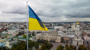 Ukrayna bayrağı dalgalanan bayrak direği yakın plan gri gökyüzünde. Ukrayna 'nın başkenti Kharkiv' deki Svyato-Pokrovsky Manastırı yakınlarındaki şehir merkezi hava manzarası