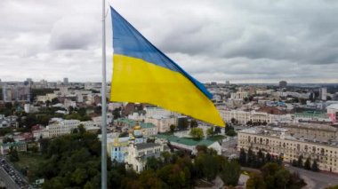 Bayrak direğinde sallanan Ukrayna bayrağı destansı gri gökyüzünde. Ukrayna 'nın başkenti Kharkiv' deki Svyato-Pokrovsky Manastırı yakınlarındaki sonbahar şehri hava manzarası