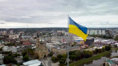 Bayrak direğinde rüzgarda dalgalanan Ukrayna bayrağı ve destansı ağır bulutlar. Ukrayna 'nın başkenti Kharkiv' deki Kutsal Annunciation Katedrali 'nde sonbaharda havadan şehir manzarası seyredilir.