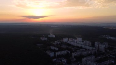 Gündoğumunda Harkiv şehir sokaklarının ve ormanın havadan görünüşü. Ormanın yakınındaki çok katlı binaların hemen üstüne uç. Güneşli ve güneşli bir sabah manzarası olsun.