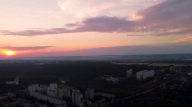 Kharkiv şehri Pavlove Pole yerleşim bölgesinin hava soldan sağa panoramik görüntüleri. Karanlık orman, çok katlı evler ve bulutlarda kızıl güneş olan gün doğumu gökyüzü.