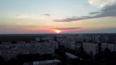 Kharkiv şehrinin Pavlove Pole semtinde sabah havası. Manzaralı bulutlu gökyüzü ve ufukta turuncu güneşi olan çok katlı binalar.