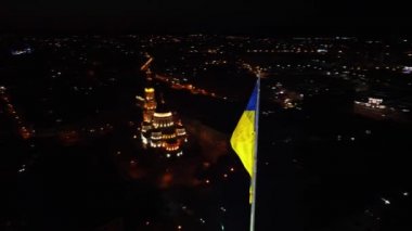 Saat yönünün tersine Ukrayna 'nın sarı ve mavi bayrağı etrafında gece bayrak direğinde dalgalanıyordu. Şehir, Ukrayna 'nın Kharkiv kentindeki Kutsal Annunciation Katedrali ile havadan görüş sağlıyor.