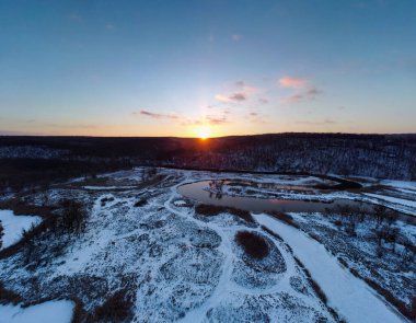 Karlı nehir üzerinde kış havası manzarası. Ukrayna 'nın Siverskyi Donets Nehri üzerindeki Zmiyevsky bölgesi. Odunsu tepenin üzerinde gün batımı güneşi parlıyor