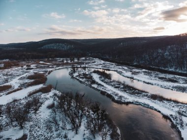 Drone 'dan karlı nehir vadisine kış havası manzarası. Ukrayna 'nın Siverskyi Donets Nehri üzerindeki Zmiyevsky bölgesi. Güneşin altında bulutların içinde karşıt nehir eğrisi
