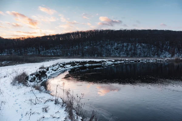 Donmuş nehir kıvrımında kış manzarası manzaralı bulutların yansıması. Siverskyi Donets Nehri Ukrayna 'da karla kaplıydı. Odunsu tepenin üstünde gün batımı bulutları
