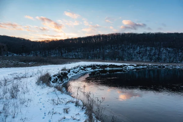 Donmuş nehir kıvrımında kış manzarası manzaralı bulutların yansıması. Siverskyi Donets Nehri üzerindeki Zmiyevsky bölgesi Ukrayna 'da karla kaplıydı. Odunsu tepenin üstündeki bulutlarda gün batımı güneşi