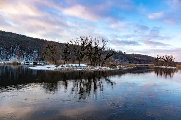 Kış nehri, karlı sahillerde çıplak ağaçların yansıması ve bulutlu bir gecede canlı bir hava. Ukrayna 'nın Siverskyi Donets Nehri üzerindeki Zmiyevsky bölgesi