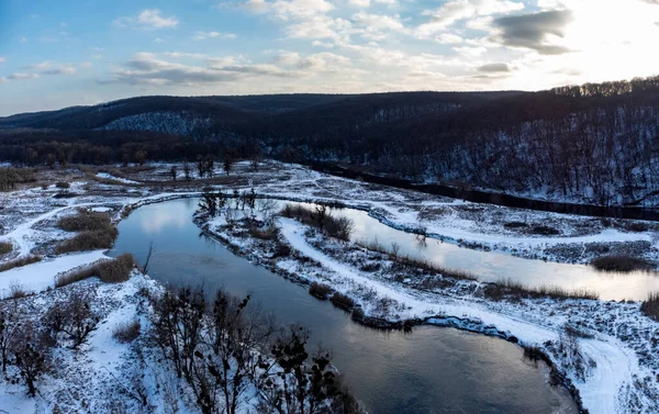 Karlı nehir vadisinde İHA 'dan kış destansı görüntüsü. Ukrayna 'nın Siverskyi Donets Nehri üzerindeki Zmiyevsky bölgesi. Güneşin altındaki zıt nehir eğrisi bulutlarda, panoramik