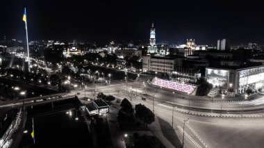 Ukrayna bayrağı ve gece yansıması ile aydınlatılmış nehir seti. Ukrayna 'nın Kharkiv kentindeki Dormition Katedrali' nin yakınındaki Lopan nehri üzerindeki şehir panorama manzarası. Gri Tonlama