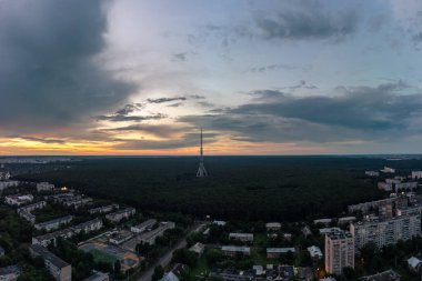 Hava panoramik akşam manzarası telekomünikasyon kulesi anteninde yerleşim bölgesi yakınlarındaki ormanda ve bulutlu gökyüzünde. Kharkiv, Ukrayna