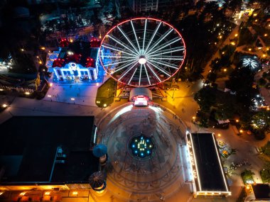 Aydınlatılmış dönme dolaba havadan bir bakış, çeşme ve cazibeyle. Kharkiv şehir merkezi dinlenme alanı akşam ışıkları altında. Gün batımında Gorky Central Park