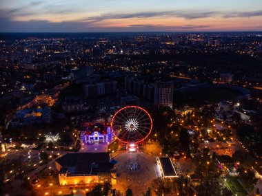 Havadan aydınlatılmış dönme dolap. Kharkiv şehir merkezi dinlenme alanı akşam ışıkları altında. Gün batımında Gorky Central Park