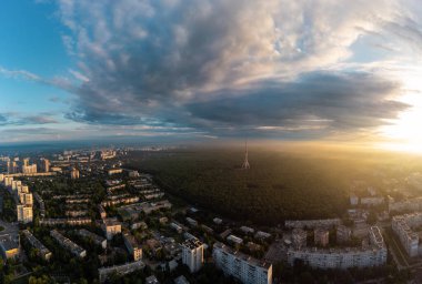 Güneşin doğuşuyla birlikte gökyüzü bulutlu ve güneşli, yerleşim bölgesi yakınlarındaki ormandaki telekomünikasyon kulesiyle hava manzarası. Kharkiv, Ukrayna