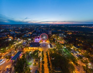 Canlı akşam şehir manzarası, dönme dolap ve eğlence panoramasında hava manzarası. Kharkiv şehir merkezinde gün batımı ışığı, eğlence Gorky Central Park, Ukrayna