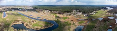 Spring aerial wide panorama view on green river delta valley from drone. Zmiyevsky region on Siverskyi Donets River in Ukraine. River curve, green forest, cloudy sky