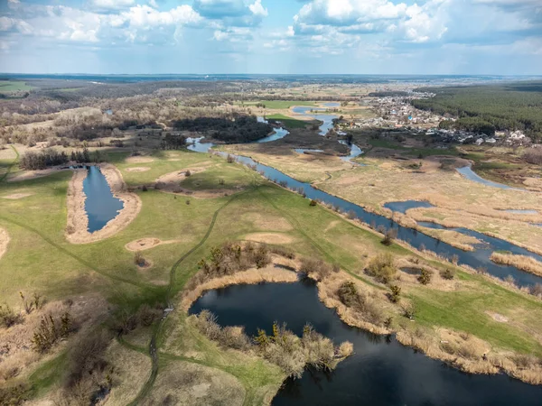 Spring aerial view on green river valley from drone. Zmiyevsky region on Siverskyi Donets River in Ukraine. River curve under cloudy sky