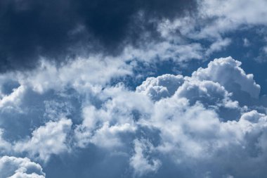 High layered white epic clouds on blue dramatic dark sky. Heavenly cloudscape background