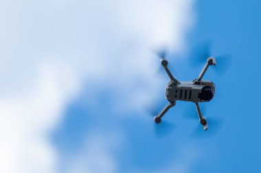 Kharkiv, Ukraine - April 22, 2021: Dji Mavic Mini 2 drone, flying in sunny day. New quadrocopter device hovering on blue cloudy sky, blurry background. Bottom view with copy space