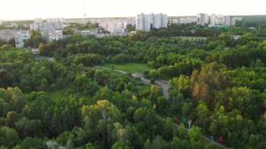 Aerial speed up backwards flying above cable car attraction at sunset in green summer Kharkiv city popular recreation park, Sarzhyn Yar. Recreation area in city center