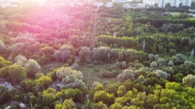 Aerial flying forward above cable car attraction at sunset in green summer Kharkiv city popular recreation park, Sarzhyn Yar. Recreation area in city center