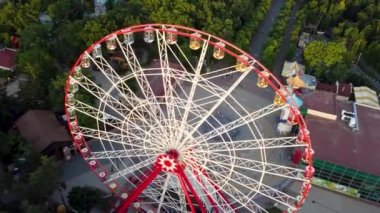 Fly above spinning Ferris wheel and attractions, aerial top view in Kharkiv city center, amusement Gorky Park. Recreation and city observation