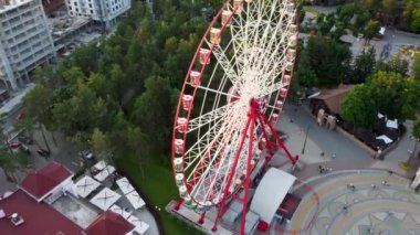 Aerial arc left footage of ferris wheel spinning at sunset, Kharkiv city center, amusement Park of Maxim Gorky. High attraction for recreation and city observation