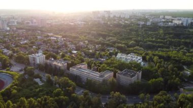 Sunny greenery in city park district, aerial view from drone. Recreation area in Kharkiv near residential buildings in sunset